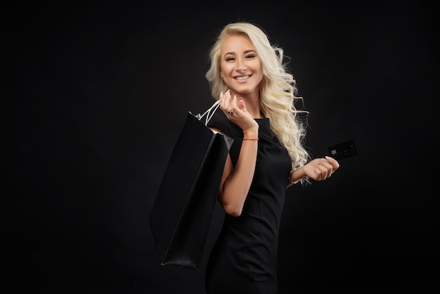 Mujer de compras con bolsa aislada en la pared oscura. Concepto de viernes negro