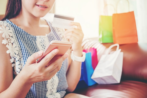 Mujer de compras en línea con teléfono inteligente con tarjeta de crédito disfrutando en casa