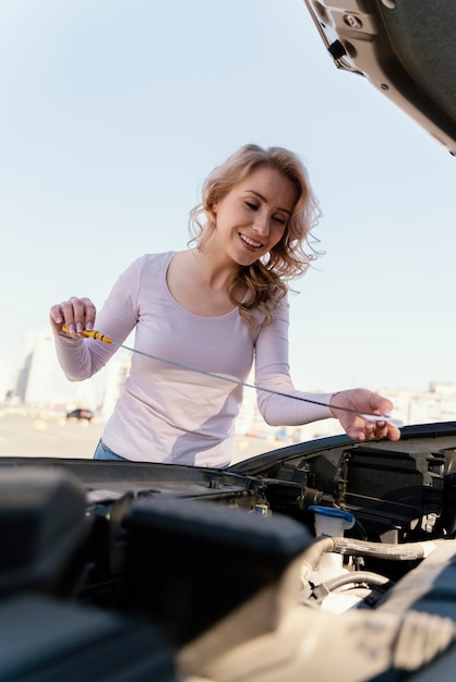 Mujer comprobando el aceite de su coche