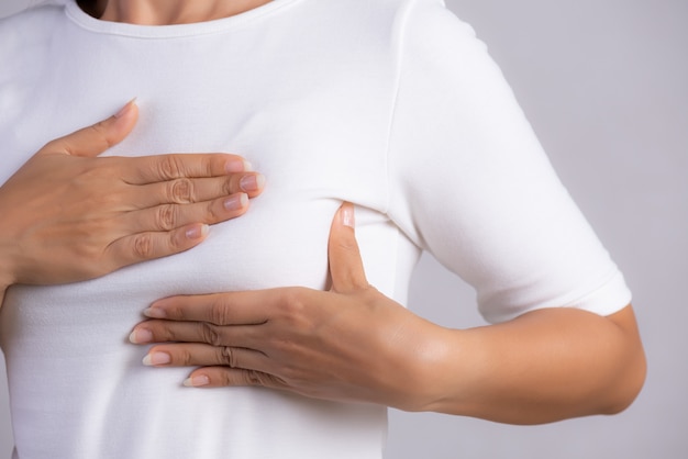Mujer comprobando bultos en su seno para detectar signos de cáncer