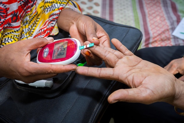 Foto mujer comprobando el nivel de azúcar con glucómetro usando una muestra de sangre en narsingdi bangladesh aprenda a usar un glucómetro concepto de tratamiento de la diabetes