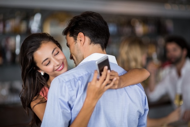 Mujer comprobando el teléfono móvil mientras abraza al hombre