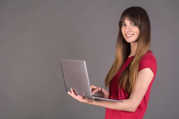 mujer, con, un, computador portatil, en, un, fondo gris, oficinista