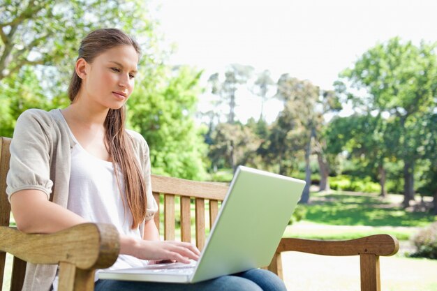 Mujer con una computadora portátil en un banco de parque