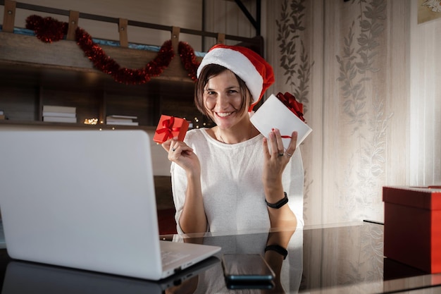 Mujer con computadora portátil en casa con sombrero de Santa Ventas de vacaciones de invierno