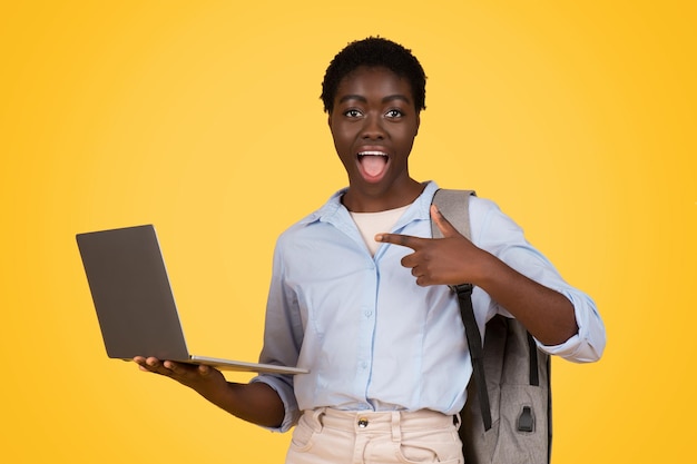 La mujer con la computadora portátil le da el pulgar en amarillo