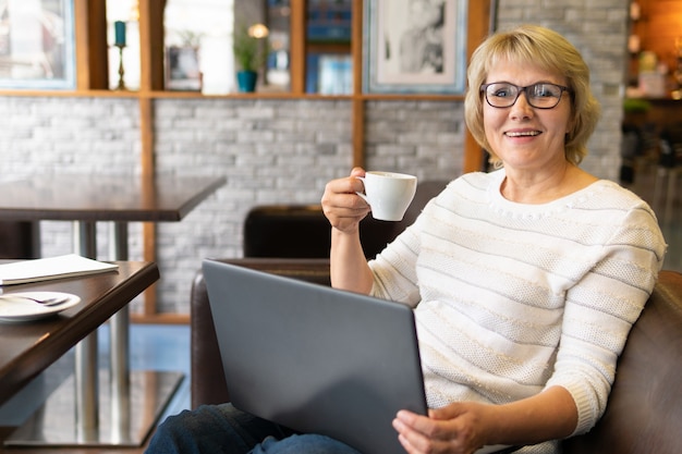 Mujer con una computadora portátil trabaja en un café en la oficina ella es autónoma