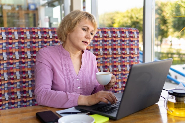 Mujer con una computadora portátil trabaja en un café en la oficina, es autónoma.