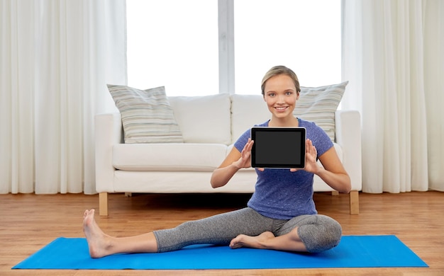 mujer con computadora tablet haciendo yoga en casa