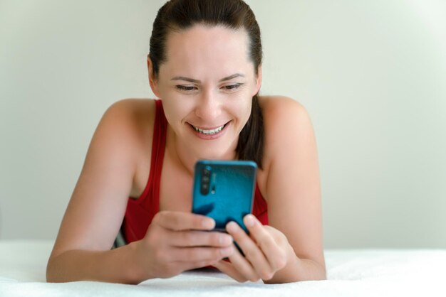 La mujer se comunica a través de la cámara de video del teléfono inteligente con una sonrisa en la cara