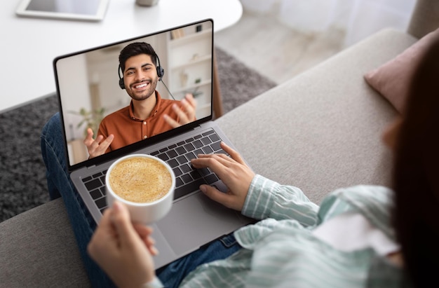 Mujer de comunicación virtual haciendo videollamadas en línea con hombre árabe en auriculares