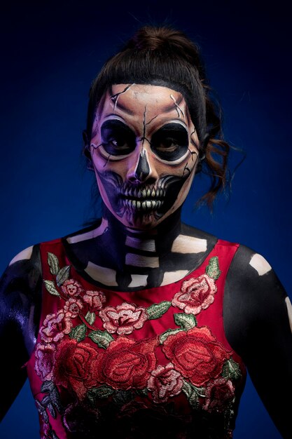 Mujer con Bodypaint de calavera con vestido Rojo y fondo azul por dia de muertos