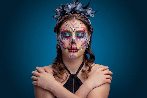 Mujer con maquillaje de catrina tradicional por dia de muertos y usando um vestido negro con fundo