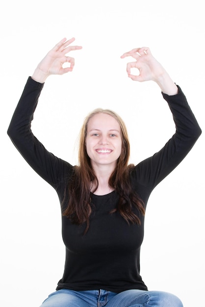 Mujer concentrada meditando con las manos arriba gesto en camisa casual de pie aislado sobre fondo blanco en el concepto de práctica de Yoga