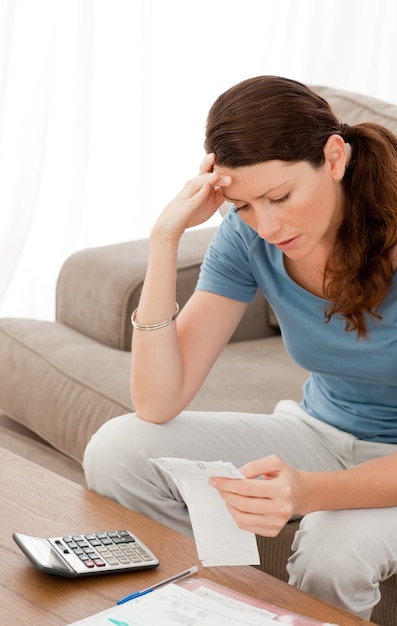 Mujer concentrada mirando sus cuentas sentado en la sala de estar