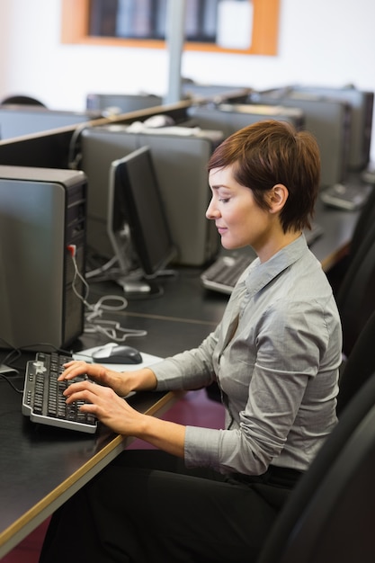 Mujer concentrada sentada en la computadora escribiendo