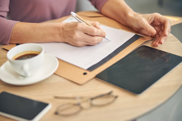 Mujer concentrada trabajando en su proyecto y esperando socio comercial en café