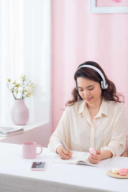 Mujer concentrada usando audífonos escribir cuaderno