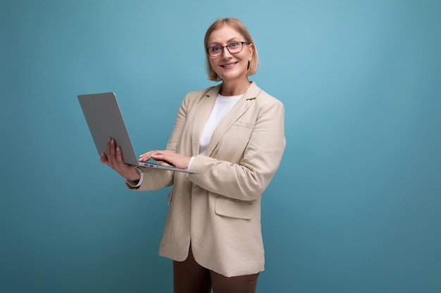 Mujer de concepto de negocios de mediana edad en una chaqueta con una computadora portátil para trabajar en un fondo de estudio con copia