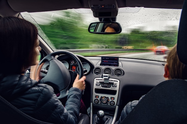 Foto mujer conduciendo un coche en una esquina bajo la lluvia