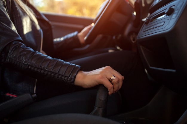 Mujer conduciendo. conductor de la mano en la transmisión y el volante. propietario arrancando su auto