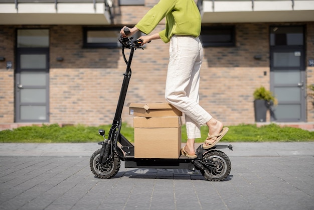 Mujer conduciendo scooter eléctrico con paquetes de cartón