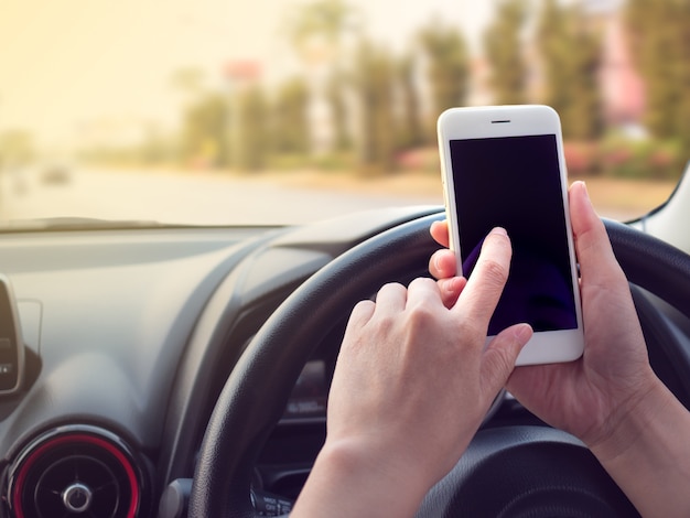 Foto mujer conduciendo y usando teléfono inteligente en la carretera