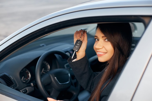 Foto mujer de conductor de coche sonriendo mostrando las llaves del coche nuevo