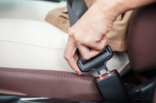 Mujer conductora abrochándose el cinturón de seguridad mientras se sienta dentro de un automóvil y conduce en el viaje de seguridad vial y el concepto de transporte