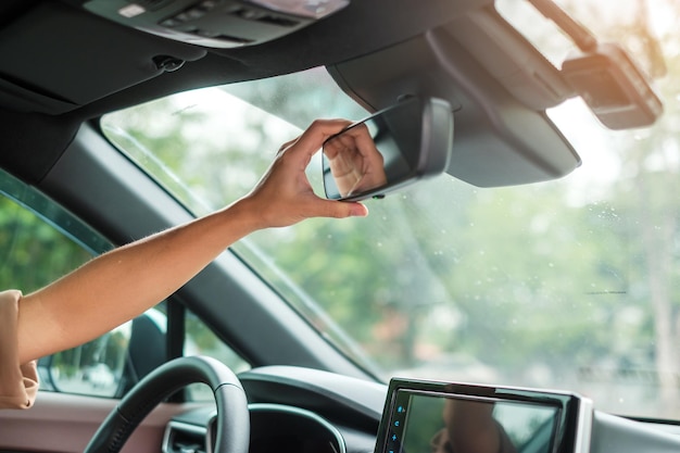 Mujer conductora ajustando el espejo retrovisor de un automóvil Viaje y seguridad Conceptos de transporte
