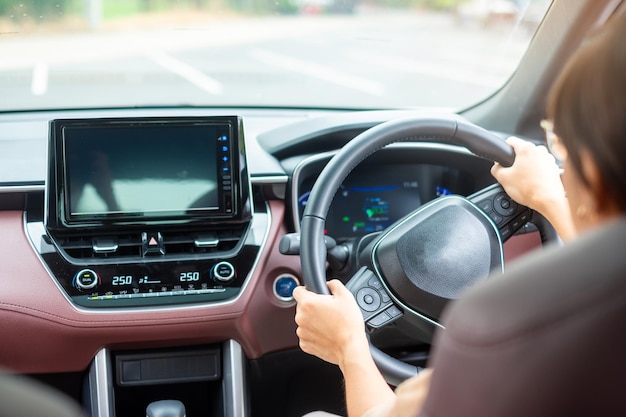 Mujer conductora conduciendo un automóvil en la carretera controlando a mano el volante en un automóvil eléctrico moderno Viaje y seguridad Conceptos de transporte