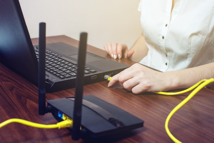 Foto mujer conecta el cable de internet al conector de la computadora portátil