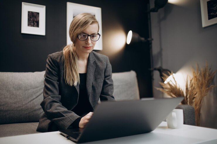 Mujer confiada en gafas trabajando en una computadora portátil personal