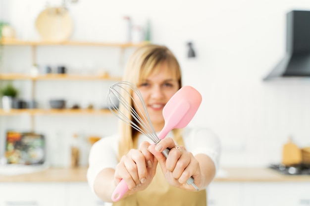 Foto la mujer confitera en el interior de la cocina blanca se recorta en manos de herramientas de confitería