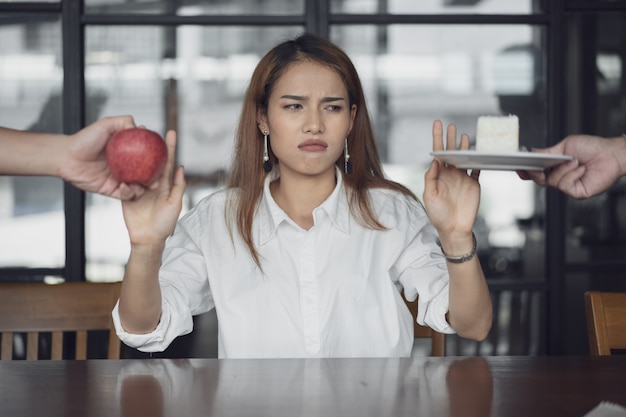 Foto la mujer se confunde con alimentos saludables y no saludables.