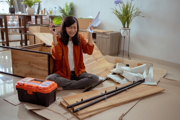 Mujer confundida mientras ensambla muebles nuevos en casa