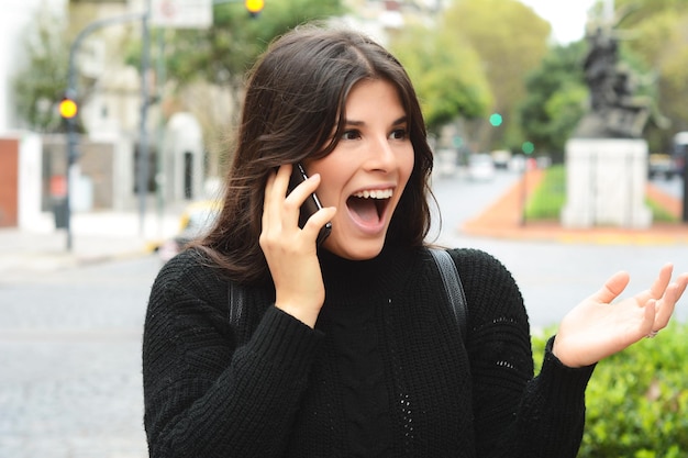 Foto mujer conmocionada hablando por teléfono móvil en la ciudad