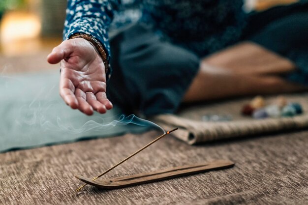 Mujer consciente practicando la meditación diaria con la quema de varitas de incienso