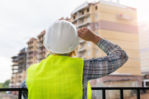 Foto una mujer constructora en un sitio de construcción inspecciona un edificio