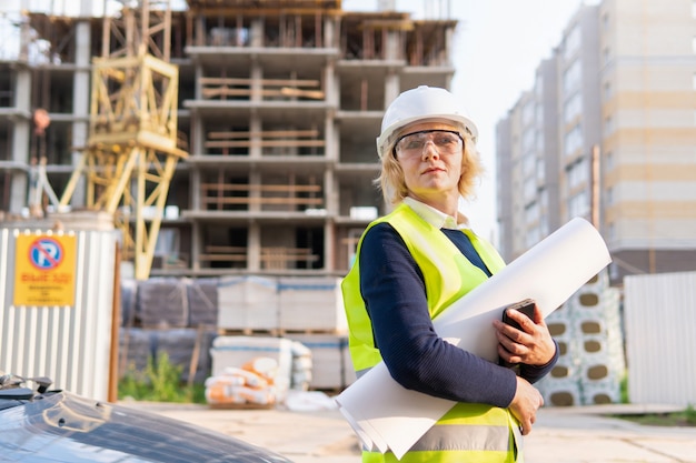 Una mujer constructora en un sitio de construcción inspecciona un edificio