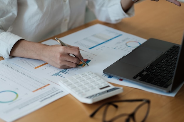 Mujer contable utiliza calculadora e informe de marketing analítico informático en el escritorio de madera en la oficina. concepto de finanzas y contabilidad.