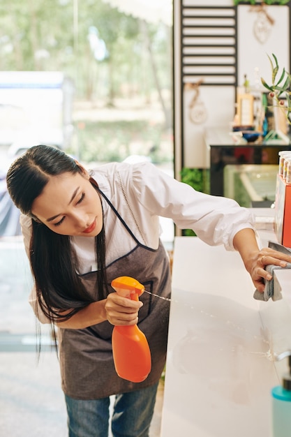 Mujer contador de coffeeshop desinfectante