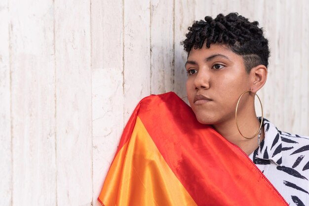 Mujer contemplativa con bandera LGBT al aire libre