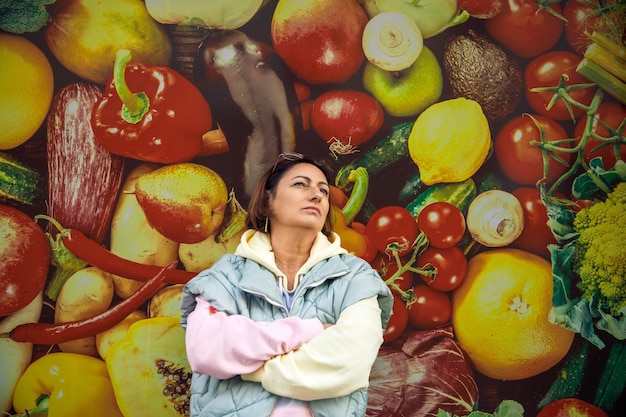 Una mujer contemplativa en un colorido mercado de verduras