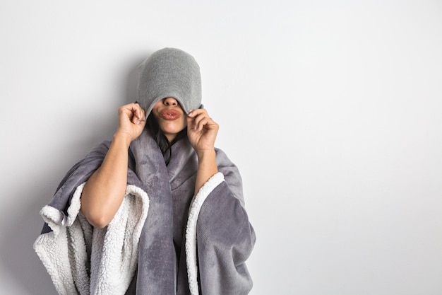 Mujer coqueteando envuelta en una manta que cubre los ojos con sombrero