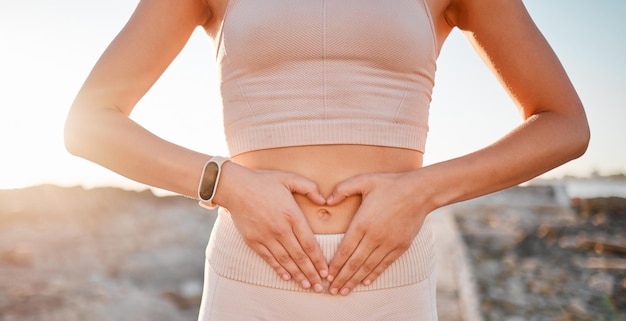 Mujer corazón y manos en el estómago para la dieta de pérdida de peso fitness o bienestar intestinal holístico Primer plano abdomen femenino amor dedos o vientre emoji de digestión corporal cuidado de la piel y ejercicio saludable en la naturaleza