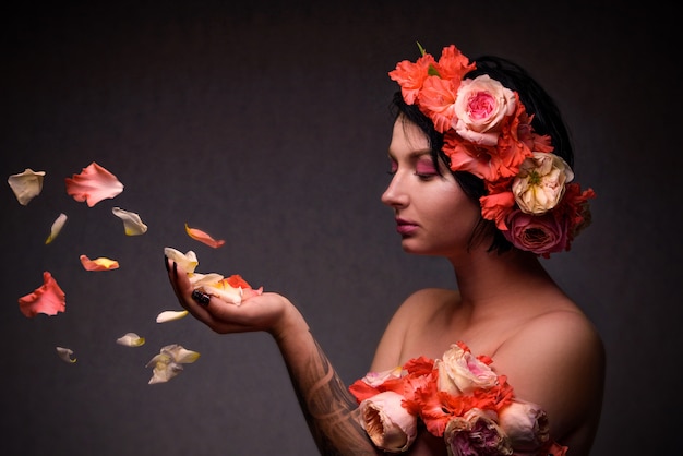 Mujer con una corona de flores y pétalos de rosa en sus manos