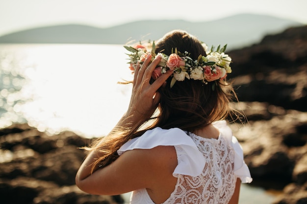 Mujer en corona nupcial en la playa. Vista trasera.