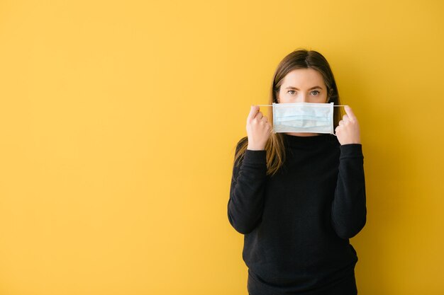 Mujer coronavirus sobre fondo amarillo en máscara quirúrgica protección facial