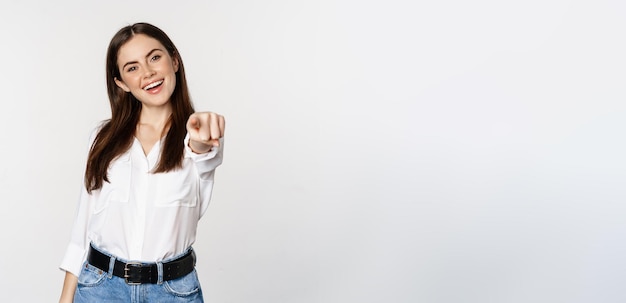 Foto mujer corporativa joven confiada señalando con el dedo a tu cámara invitando a elegir felicitar a stan